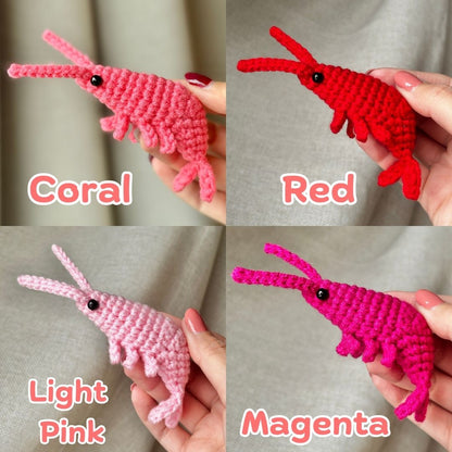 Four crochet shrimp toys in different colors held by hands against a neutral background.