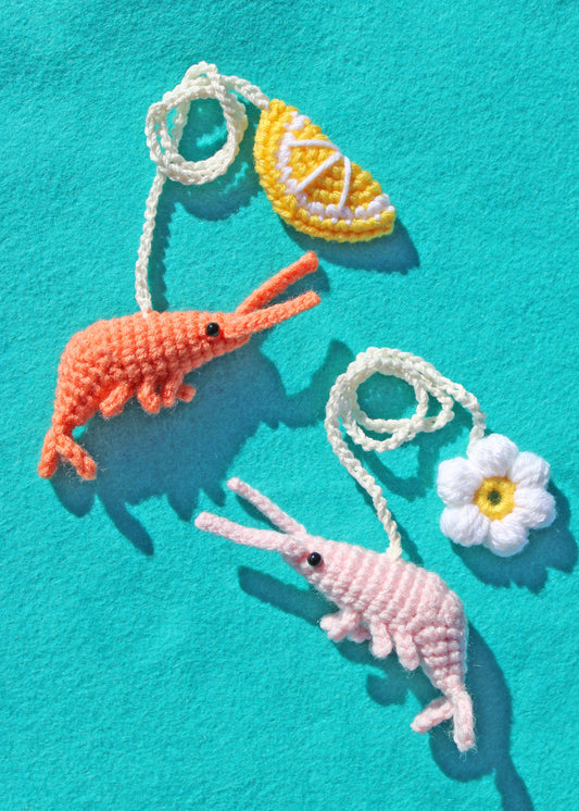 Crocheted shrimp and lemon with a flower on a turquoise background
