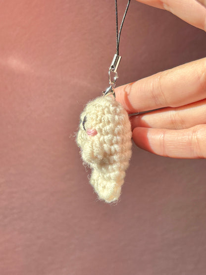 Hand holding a small crocheted heart charm against a plain background